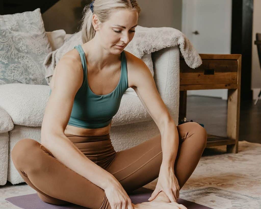 Dr. Heather Iverson stretching on a yoga mat at home, demonstrating daily movement habits that support healthy aging, mobility, and longevity.